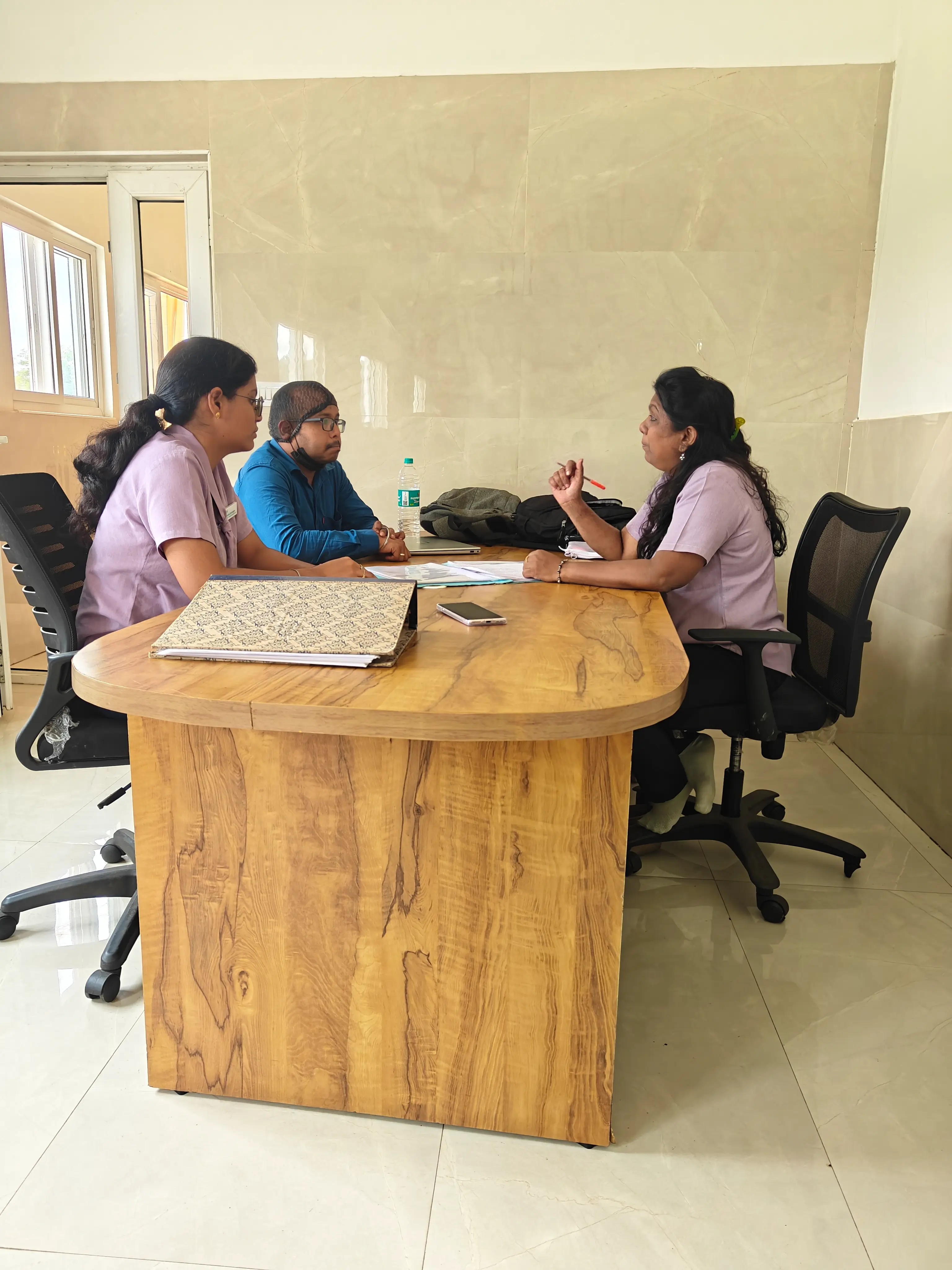 Colleagues seated around a wooden table in a bright office holding a working discussion.