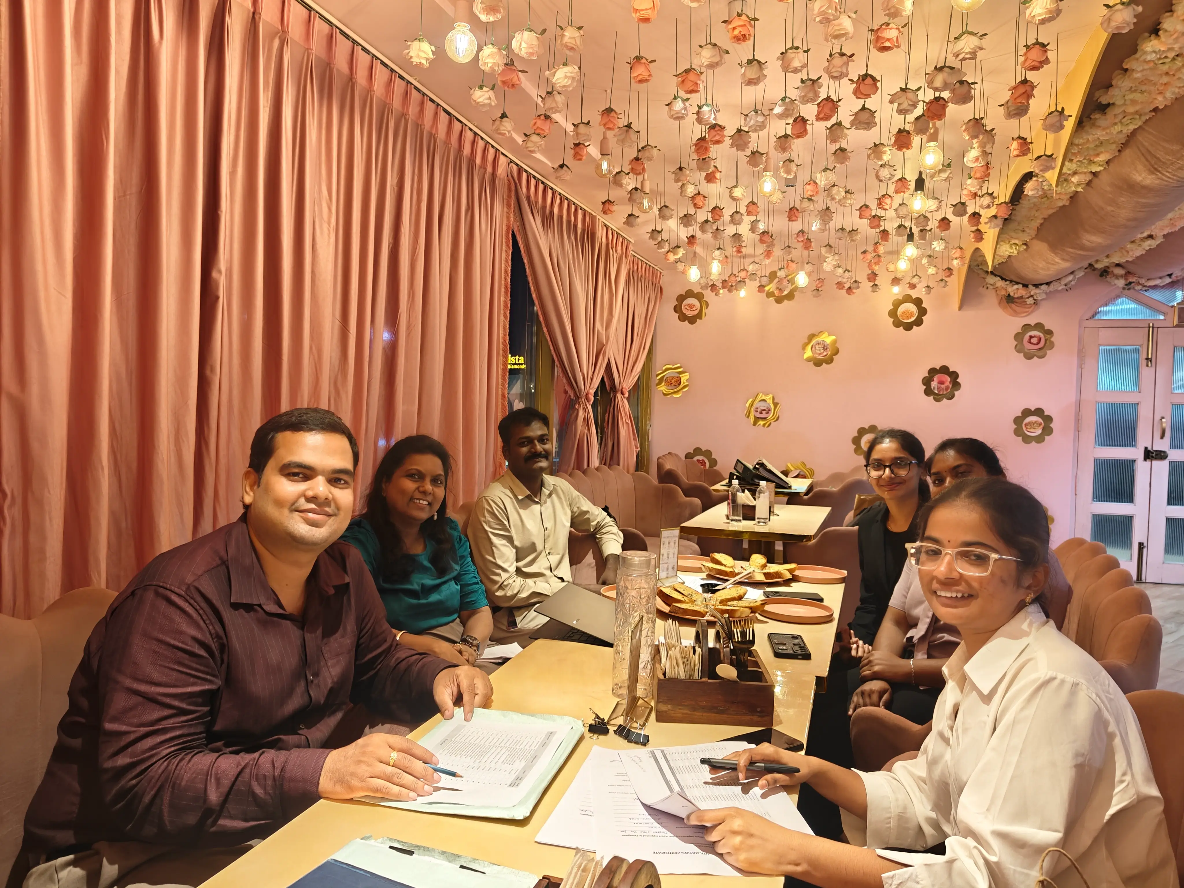 Team seated around a restaurant table reviewing printed documents and notes together.